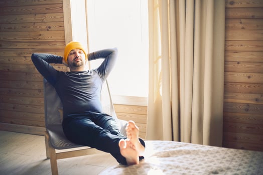 Stylish hipster man sitting on armchair with close eyes in wooden house photo