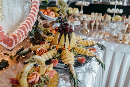 A table with a variety of fruits and desserts, including bananas, strawberries, and grapes. The table is set for a special occasion, and the presentation is elegant and inviting photo