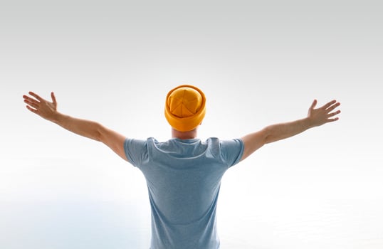 Young man in a gray shirt with a yellow hat is standing with his arms outstretched. Feel the freedom. photo