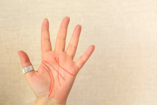 Palmistry. Female palm with life lines drawn with felt-tip pen isolated on light beige background photo