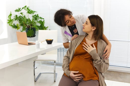 a woman is sitting on a desk while a man is standing next to her photo