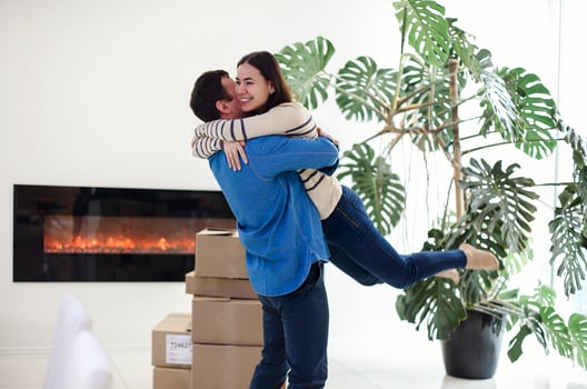 Happy couple with cardboard boxes hugging in new home photo