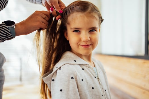 Mother is making of braids on little daughter's head. photo