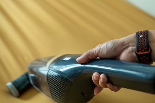 Asian woman's hands using vacuum cleaner on sofa photo