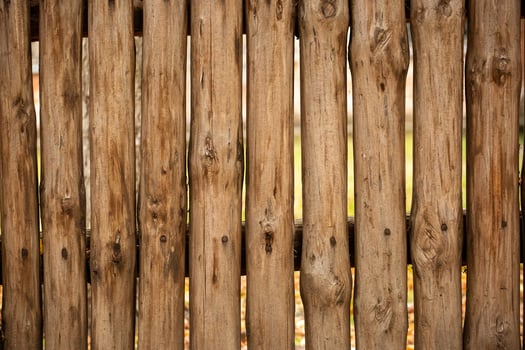 A fence made of roughly processed boards. A palisade of rough logs. Wood back photo