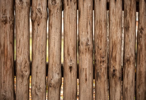 A fence made of roughly processed boards. A palisade of rough logs. Wood back photo