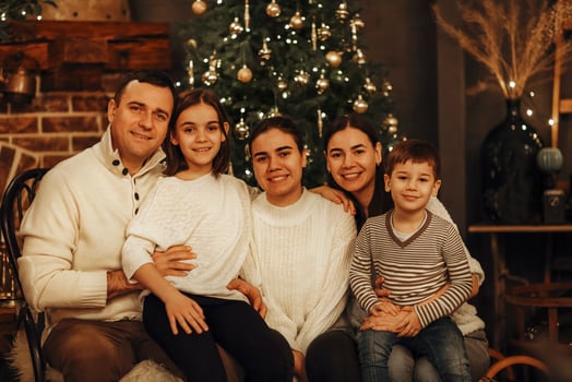 Mother, father and children decorate the tree in room. Loving family indoors photo