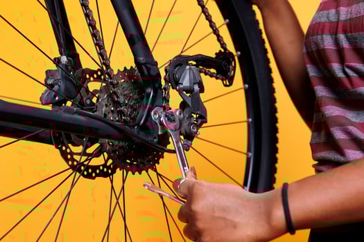 Detailed image showing pair of hands doing maintenance by skillfully fixing bicycle wheel with essential work tool. Close-up shot of black woman gripping spanner for tightening bicycle parts. photo