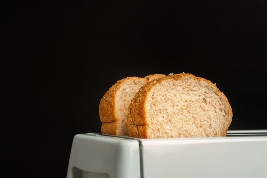 Rich and soft whole wheat bread in the toaster with a black background. Close-up photo. Space for text photo