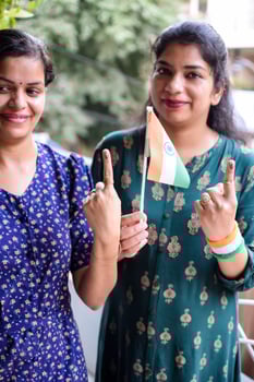 Two Smart young lady showing her ink-marked fingers after casting votes in front of polling booth of east Delhi area for general Lok Sabha Elections 2024 photo