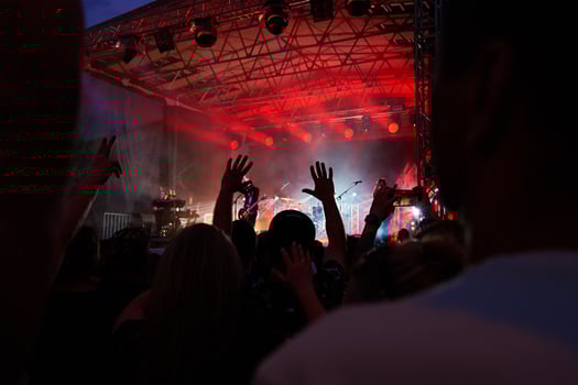 Silhouettes of crowd at concert in front of stage with bright spotlights. People enjoy live music at the band's performance. Concert hall with musicians on stage and fans during music festival photo