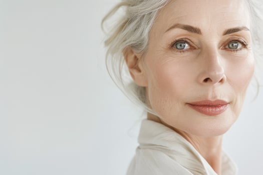 Portrait of a beautiful elderly woman in close-up. A picture of the face of a mature blonde with clean, fresh skin on a light background. photo
