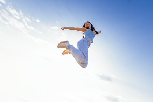 Charming Asian girl with long wave hair in casual clothes is jumping and laughing outdoors photo