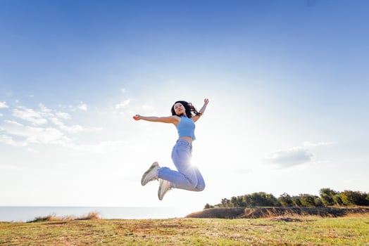 Charming Asian girl with long wave hair in casual clothes is jumping and laughing outdoors. Young cheerful Korean woman have fun in nature. photo