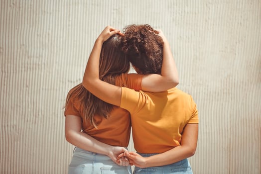 Strong female friendship. Rear view two girls best friends holding hands behind back and hugging photo