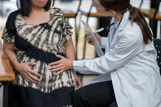 A doctor consults a pregnant patient, taking notes while discussing her symptoms and well-being during a prenatal visit. photo