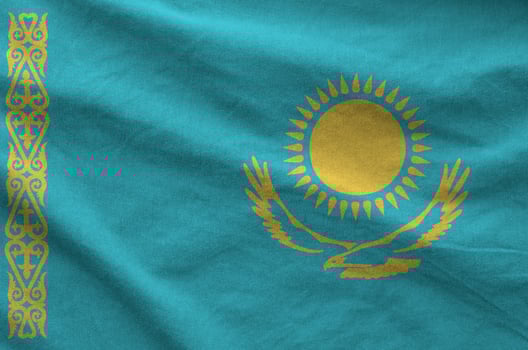 Kazakhstan flag depicted on folded wavy fabric of old cloth photo