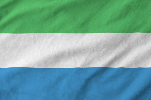 Sierra Leone flag depicted on folded wavy fabric of old cloth photo