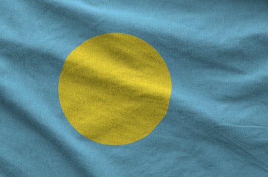 Palau flag depicted on folded wavy fabric of old cloth photo