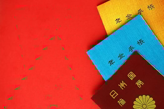 Japanese pension insurance booklets on table with passport. Blue and orange pension book photo