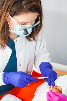 Doctor suturing a patient during a small surgery. Dermatologist carrying out a removal of benign skin lesion on the face of a young male patient. photo