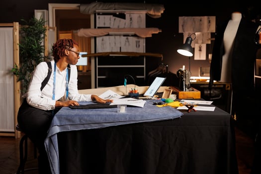 African american seamstress apprentice amuzed by creative handdrawn sketches made by master fashion designer she has to manufacture. Happy tailor creating sartorial bespoke collection photo