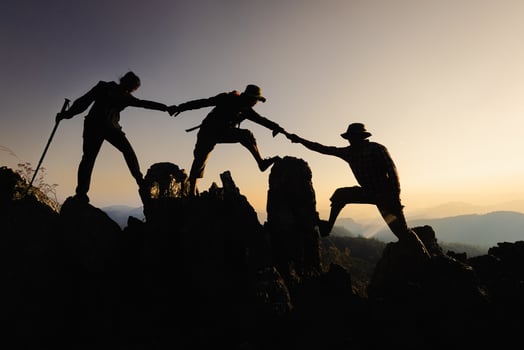 Silhouette of a group of climbers on a mountaintop. Success, teamwork and unity. photo