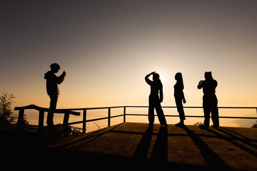 Silhouette of a group of four tourists taking pictures on a mountain during sunset. photo