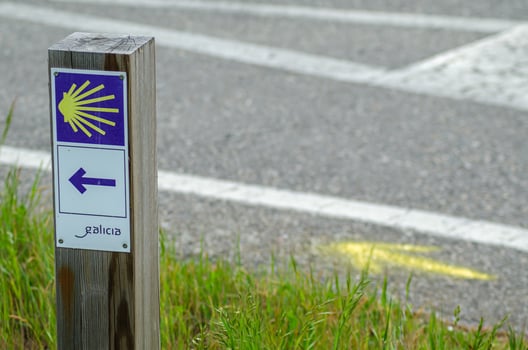 signpost of the Camino de Santiago in Galicia and yellow arrow painted on the ground. Spain photo