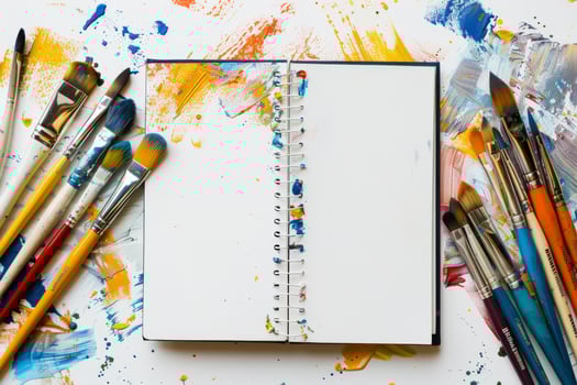 In an artists colorful workspace, an open sketchbook holds potential, vibrant brushes await ideas, and paint splatters showcase unique creativity and imaginative expression, ready to be unleashed photo