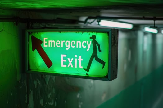 A vibrant green emergency exit sign shines brightly, directing individuals towards safety in a shadowy corridor. photo