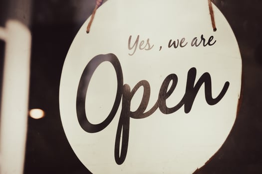Close-up of a Yes We Are Open Sign Hanging on a Glass Door of a Shop or Cafe photo