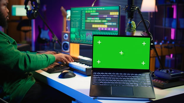 Professional artist operating on daw software in home studio, using a green screen layout next to him. Producer editing his audio recordings by applying mixing and mastering techniques. Camera B. photo