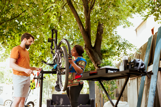 Outdoor maintenance activity with sports-loving multiethnic couple cleaning and repairing bicycle parts. Active dedicated interracial couple doing annual summer bike maintenance. photo