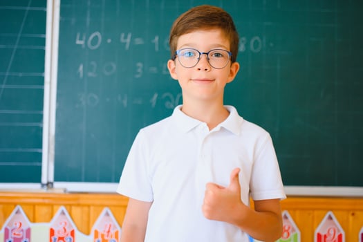 Cute schoolboy near blackboard in classroom photo