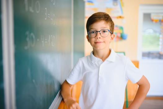 Cute schoolboy near blackboard in classroom photo