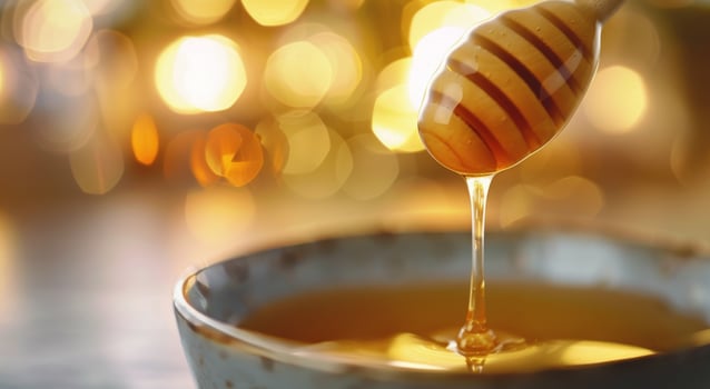 Golden Honey Dripping From Spoon Into Small Bowl During Bright Morning Light photo
