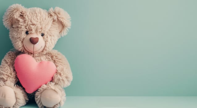Adorable Teddy Bear Holding Pink Heart Against Soft Blue Background photo
