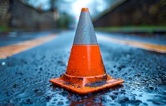 Wet orange traffic cone on a rainy road in a suburban area. photo