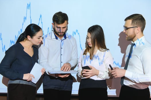 Business Conference Meeting Presentation Businessman does Financial Analysis talks to Group of Businessspeople. Projector Screen Shows Stock Market Data, Investment Strategy, Revenue Growth photo