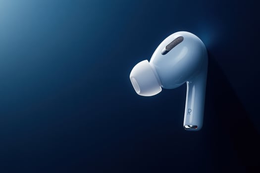 A stylish wireless earbud elegantly suspended, showcasing its sleek design against a rich blue background. photo