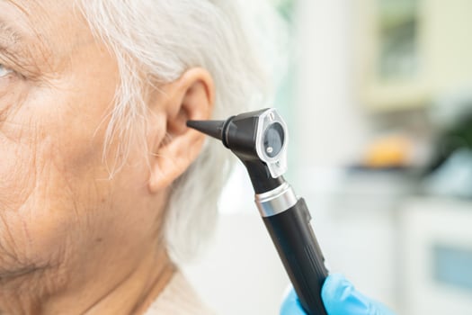Audiologist or ENT doctor use otoscope checking ear of asian senior woman patient treating hearing loss problem. photo
