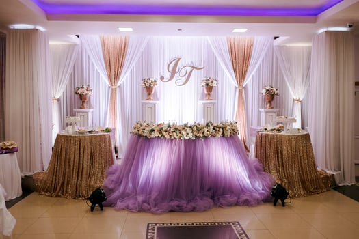 A wedding reception with a purple table and gold tablecloths. The table is decorated with flowers and the room is lit with purple lights photo