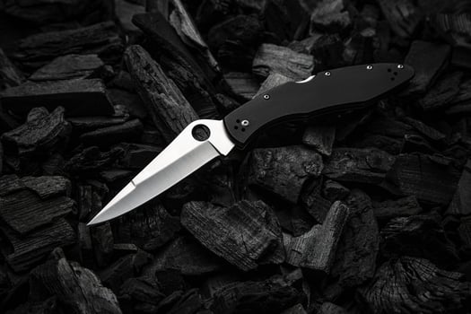 Modern knife with a silver blade. Hunting, military folding knife on smoldering charcoal. Black back. photo