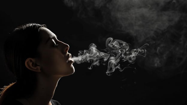 Girl releases cigarette smoke on a black background, close-up photo