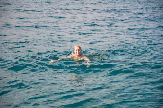 Active laughing young woman enjoying swimming in refreshing clear sea water on sunny day, vacation travel and relaxation concept, photo