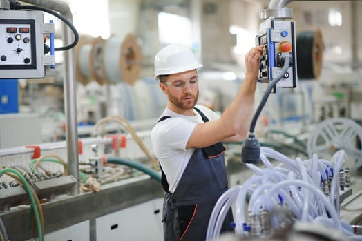 Smiling and happy employee. Industrial worker indoors in factory. Young technician with hard hat photo