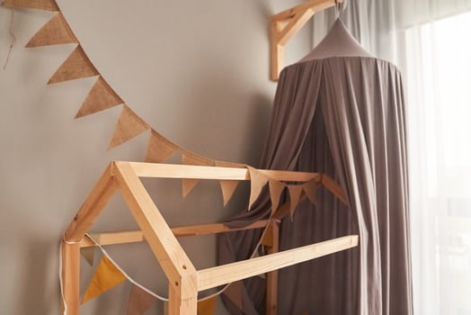 Decor in domestic, cosy, modern childrens bedroom with wooden bed like a house, with fabric canopy for children, brown party bunting flags. Background with copy space. Concept of interior design photo