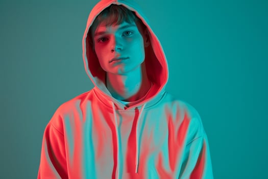 Trendy Male Model in Neon Coral Hoodie with Neon Teal Background Stylish and energetic Males portrait with Urban edge photo