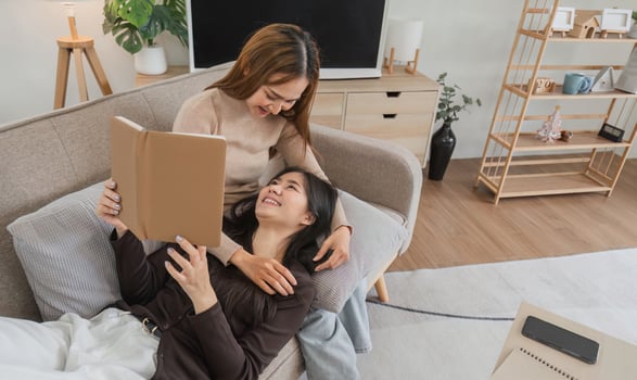 Lesbian and LGBT Couple Relaxing Together in Modern Living Room, Enjoying Quality Time and Reading a Book photo